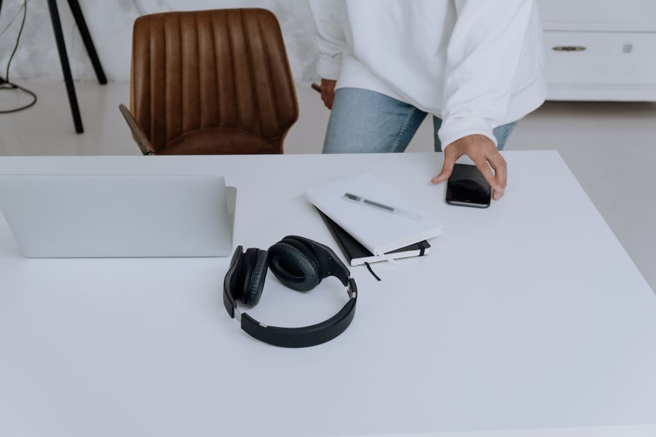 Clean and modern home office desk setup with laptop, headphones, notebook, and smartphone.